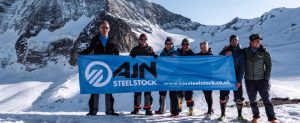 AJN sponsored event participants holding AJN banner in the snowy mountains