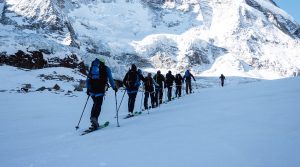 Charity skiers trekking across the mountains in a single line
